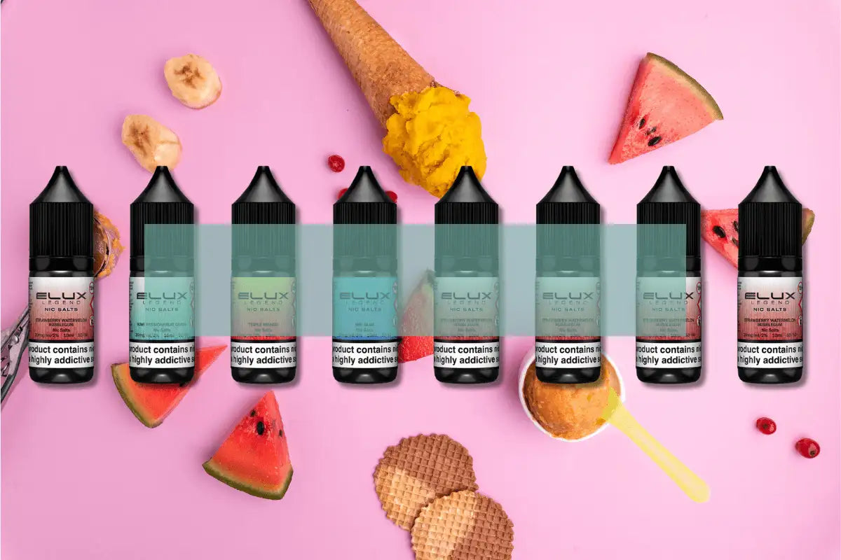 Six black-topped, transparent bottles of ellux nic salts e-liquid in various colored liquids are arranged on a pink surface.